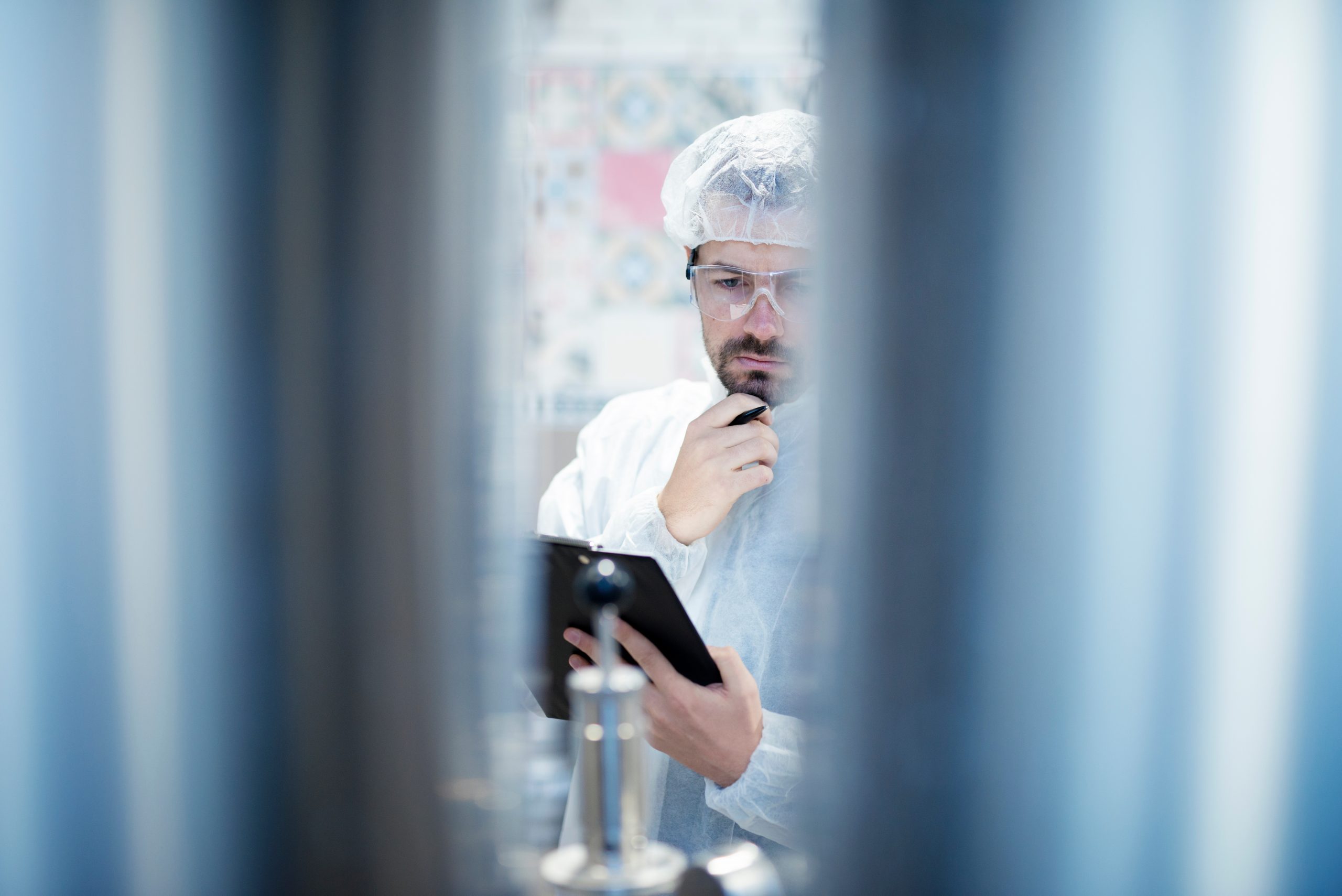 Technologist in protective white suit working in food processing