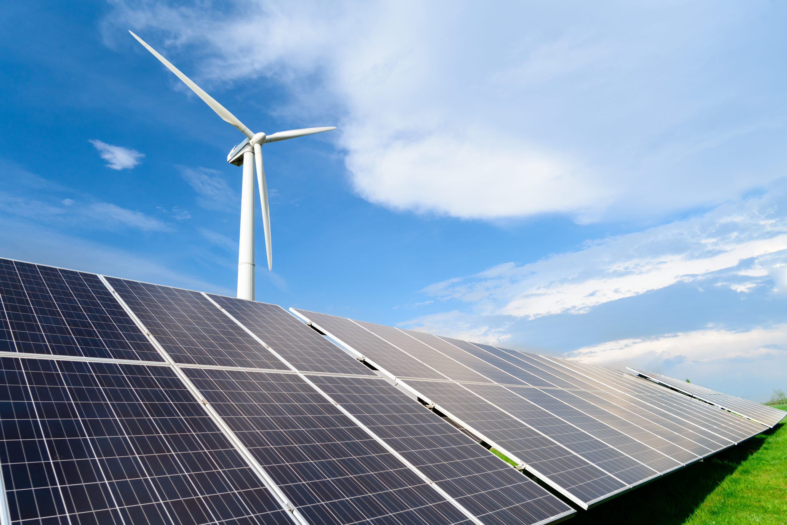 Solar energy panels and windmills against blue sky on summer day